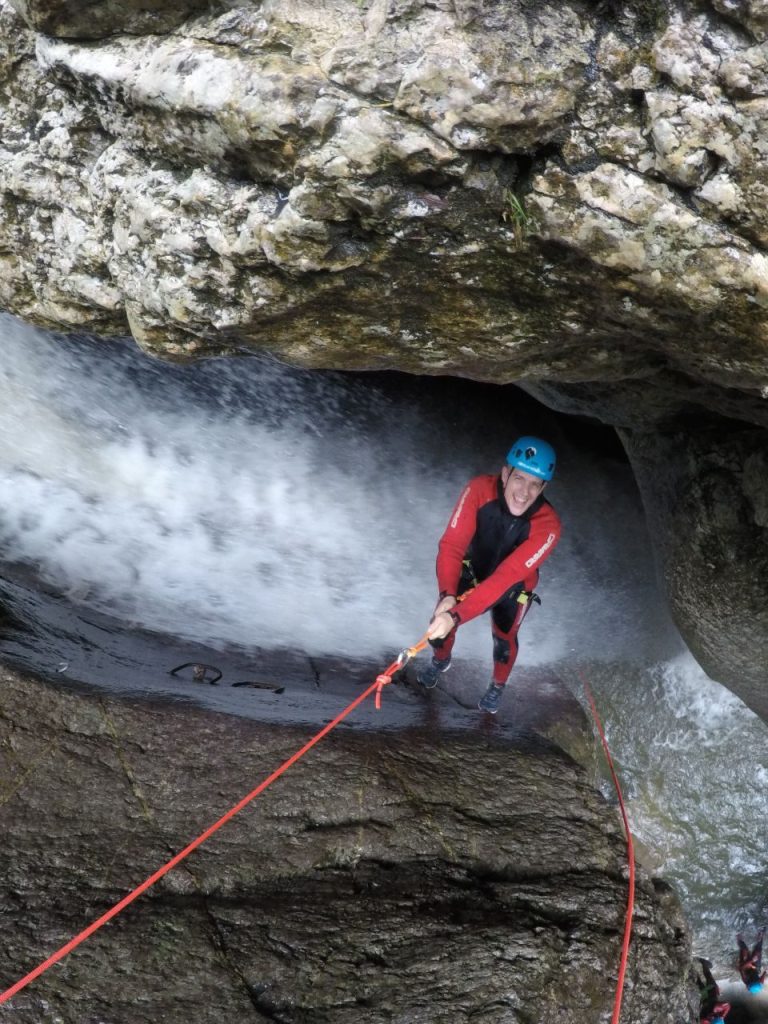 Kletterer beim Canyoning in deiner Nähe in einer engen Höhle, gesichert mit Seil und Kletterhelm in der Starzlachklamm Allgäu